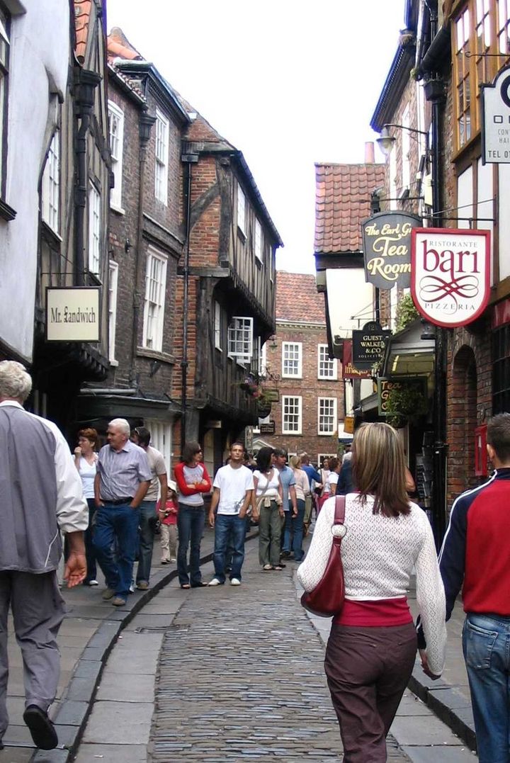 The medieval timber-framed Shambles street in York, with jettied upper storeys overhanging cobbles and the Earl Grey Tea Rooms sign in view, the street that houses 42 Shambles